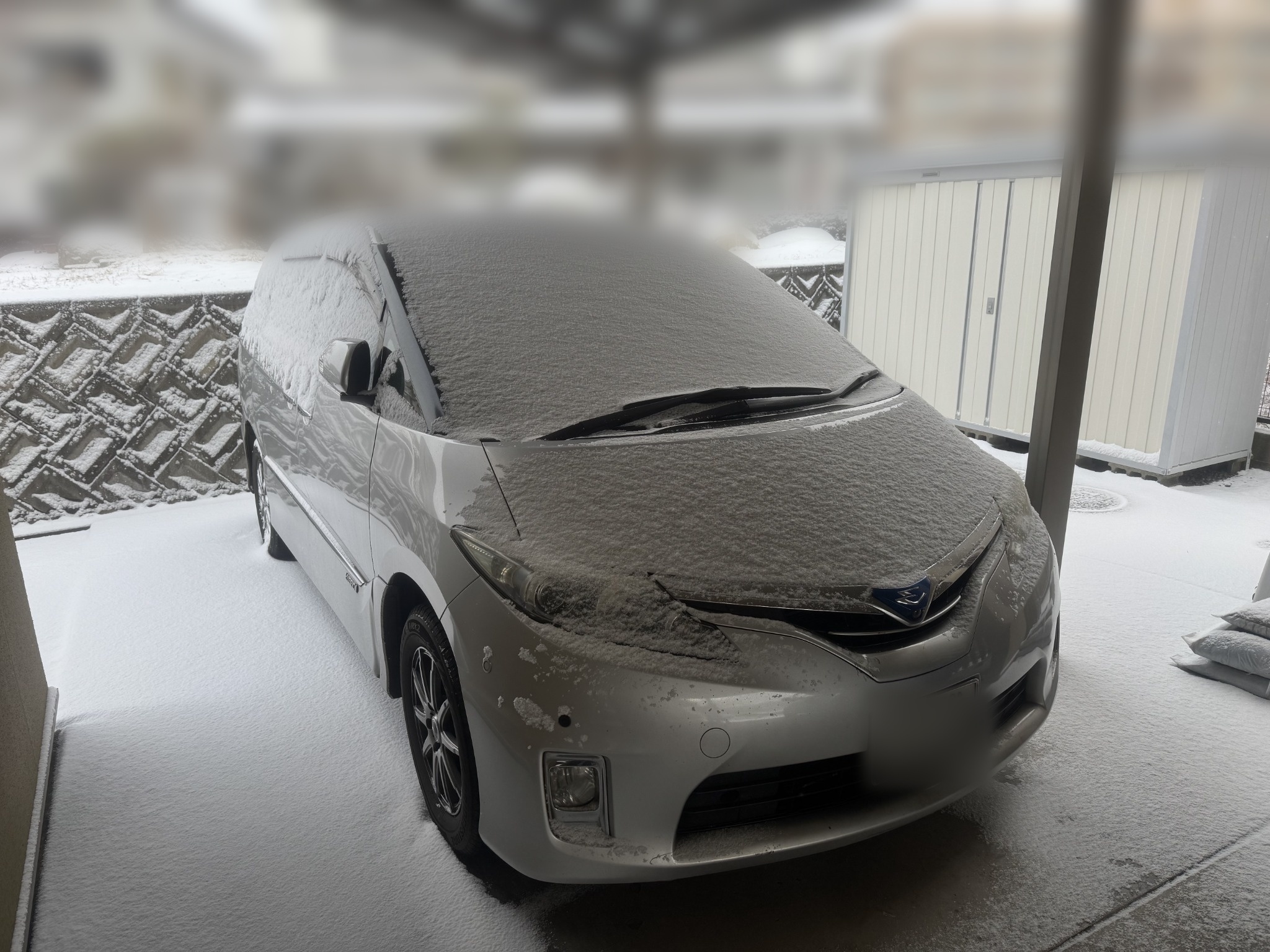 雪の日にカーポート下に停まるエスティマハイブリッド